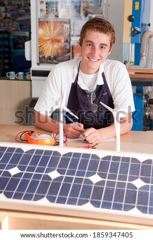 A portrait shot of a young boy smiling at camera while learning about wind power and solar panels in a vocational school.