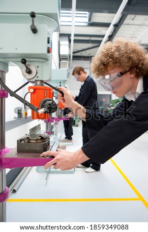 A portrait shot of a young boy using a drill machine in a vocational school.