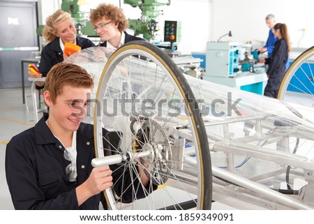A medium shot of a young boy working on a cycle wheel in a vocational school.