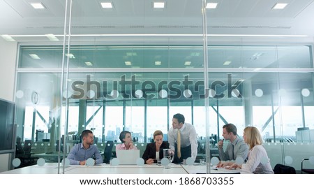 A horizontal view of business people through a glass door having a serious meeting in the conference room