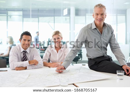 A group portrait of smiling businessmen and businesswoman reviewing a map during a meeting in the conference room
