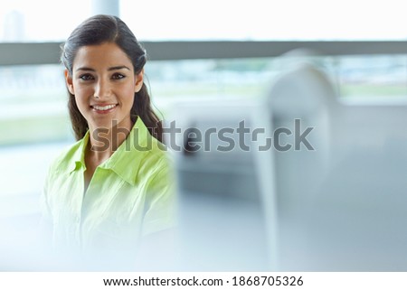 A portrait of a smiling brunette businesswoman in formal clothes sitting in the office under selective focus