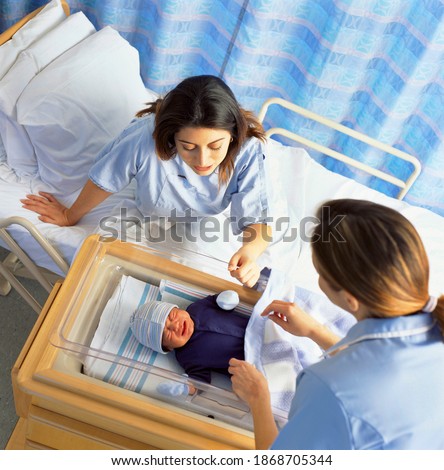 A high angle view of a Nurse and a mother checking on her crying baby sleeping in the hospital crib