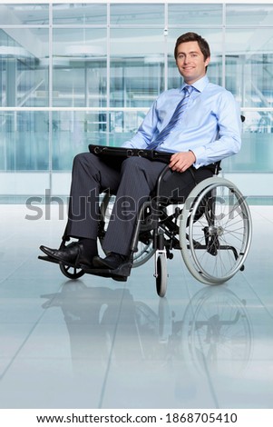 A full-length vertical portrait of a smiling businessman sitting in a wheelchair while carrying an office bag on his lap