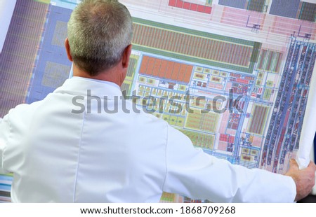 A horizontal rear view of an Engineer examining the circuit diagram in a laboratory