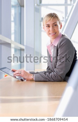 A vertical view of a confident businesswoman in formal suit using a digital tablet