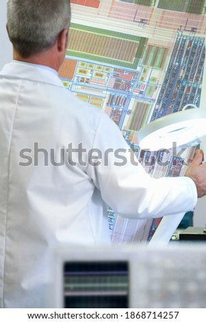 A cropped rear view of an Engineer examining the circuit diagram in a laboratory