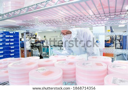 A horizontal view of a scientist in clean suit checking batches of silicon wafers in a laboratory