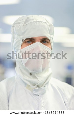 A frontal close-up portrait of an expert scientist in a clean suit