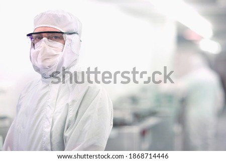 A portrait of a scientist wearing a clean suit in the silicon wafer manufacturing laboratory with a blurred background
