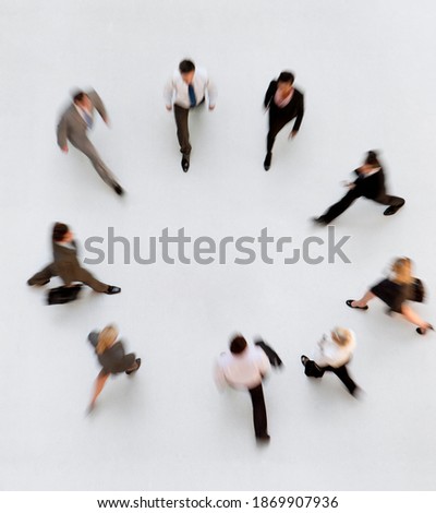 Overhead shot of motion blur of businesspeople in a ring walking towards the center.