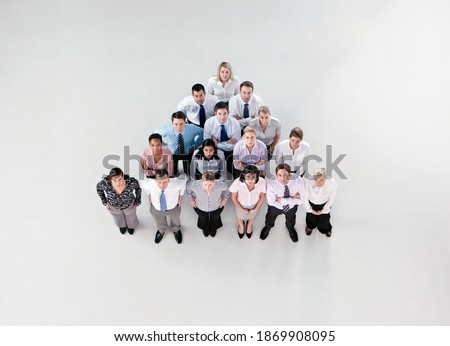Overhead shot of a group of businesspeople standing in a pyramid formation looking at the camera.