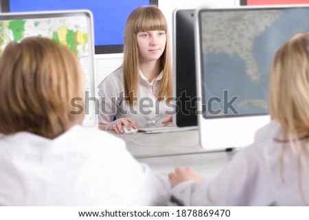A school girl wearing white uniform in selective focus working on a desktop computer in a computer lab