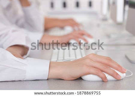 Medium close up of hands of students holding a computer mouse in a school lab