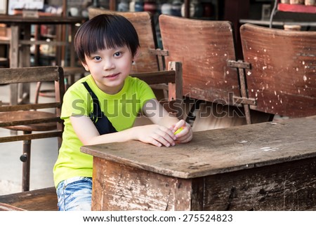 Little asian boy smiling looking away while on table