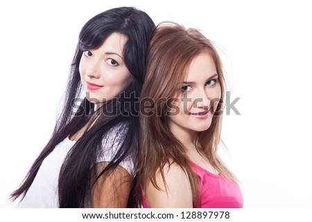 Two young girls standing back to back againt the white.