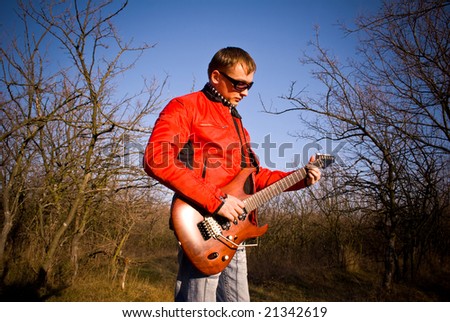 Guitarist plays electric guitar outdoor.