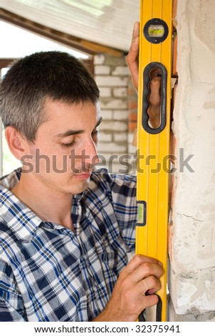 A construction man checking the level of a wall