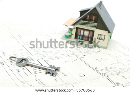 A model home and house key on architectural floor plans