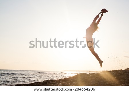 Woman jumping on the beach at the sunset