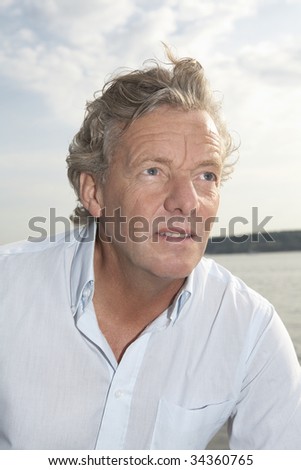 A handsome man in his fifties relaxing near by a sea