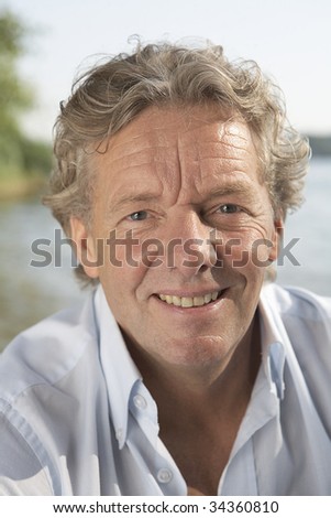 A handsome man in his fifties relaxing near by a sea