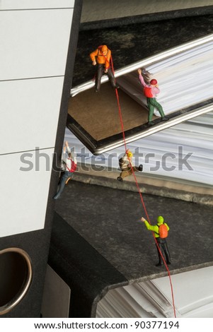 Miniature Mountaineers Climbing Office Files, miniature models of mountaineers rope climbing up a set of randomly positioned files.