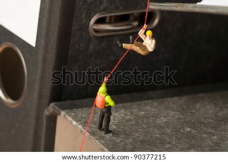 Abseiling On Office Files, miniature models of mountaineers abseiling down off an office file.