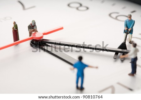 Countdown To Midnight And New Year. A team of miniature toy figurines tries to push the minute hand to midnight, closeup on a portion of a clock face.