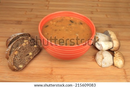 Goulash mushrooms in bowl on wooden table with fresh mushrooms sliced bread.
