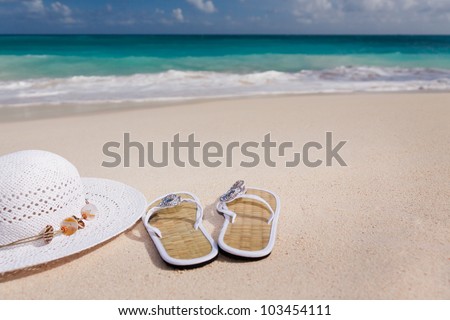 white hat and flip-flops on the beach with blue sea in the background