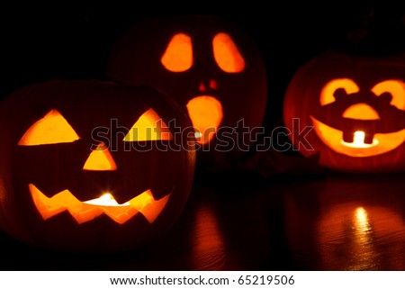 three jack-o-lantern pumpkins glowing in the dark