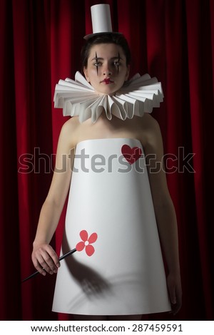 woman pierrot with paper clothing, flower, collar, cylinder, heart and red curtain