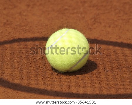 Shadow of a tennis racket on a ball on clay