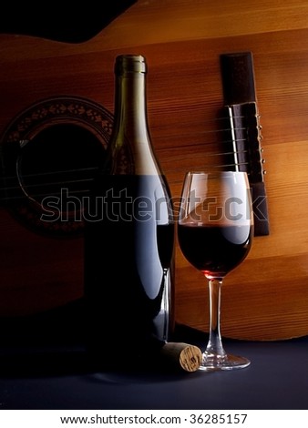 glass of wine and a bottle with a guitar as a background