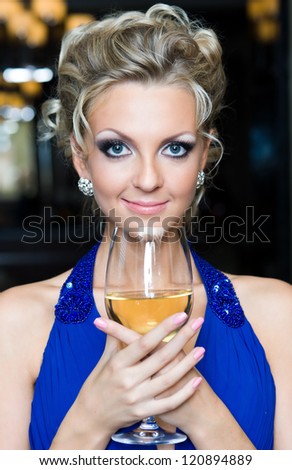 Beautiful woman with a glass of wine in an evening dress