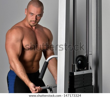 Strong man with naked torso doing exercises in a sport club.