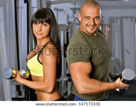 Man and woman are doing exercises in a sport club.