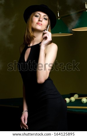 Portrait of the beautiful smoking woman in the billiards club