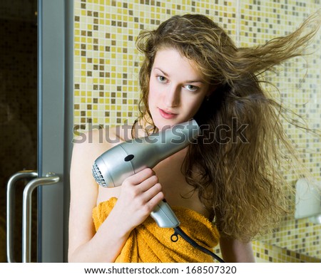 Beautiful woman drying her wet hair in the bathroom
