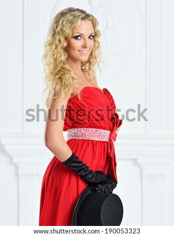 Beautiful woman in a red evening dress with man\'s hat.