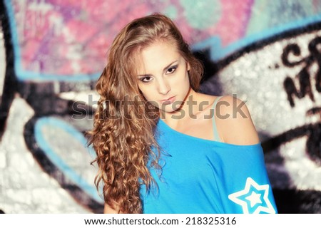 Portrait of the beautiful young woman with wall graffiti background . Street photoshoot .