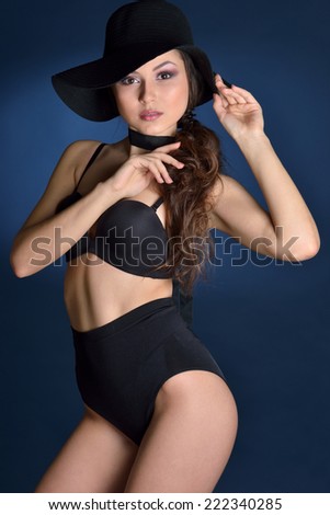 Beautiful woman in a black lingerie and big hat. Studio shooting.