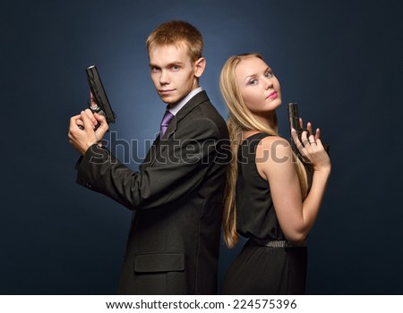 beautiful couple in evening dresses  with a guns. Photoshooting in criminal and a spy style.