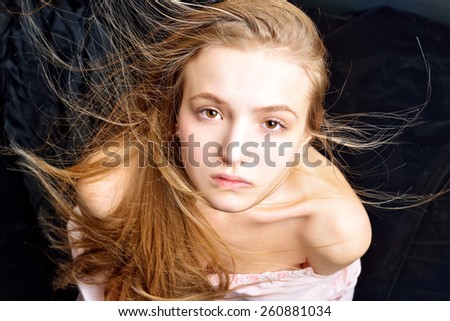 Portrait of the beautiful blonde woman with flying long hair. She is with naked shoulders  in studio .