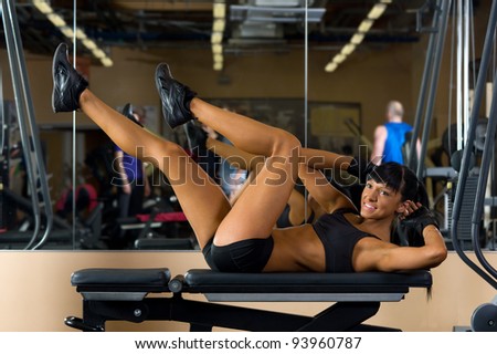 Beautiful woman is doing exercises at the gym in the sport club.