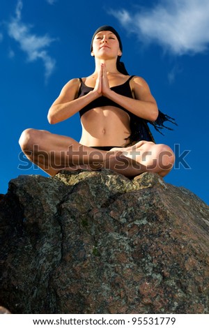 Young beautiful woman sitting in lotus pose on the beach