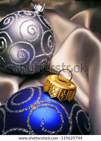 Christmas New Year balls on silk background. Light and dark blue Christmas decoration on milky silk.
