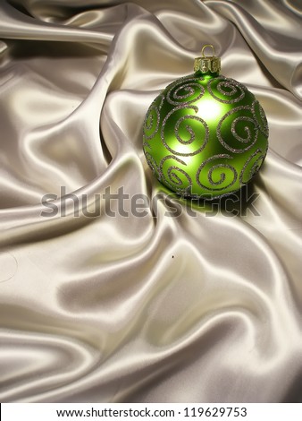 Christmas New Year balls on silk background. Green Christmas decoration on milky silk.