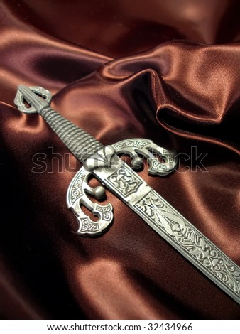 Handle of ancient beautiful sword on a background silk drapery close